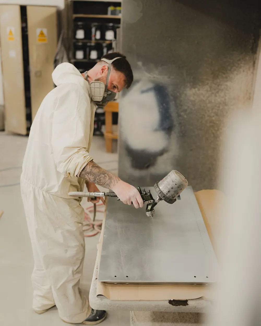 Pintor com equipamento de proteção pintando painel metálico